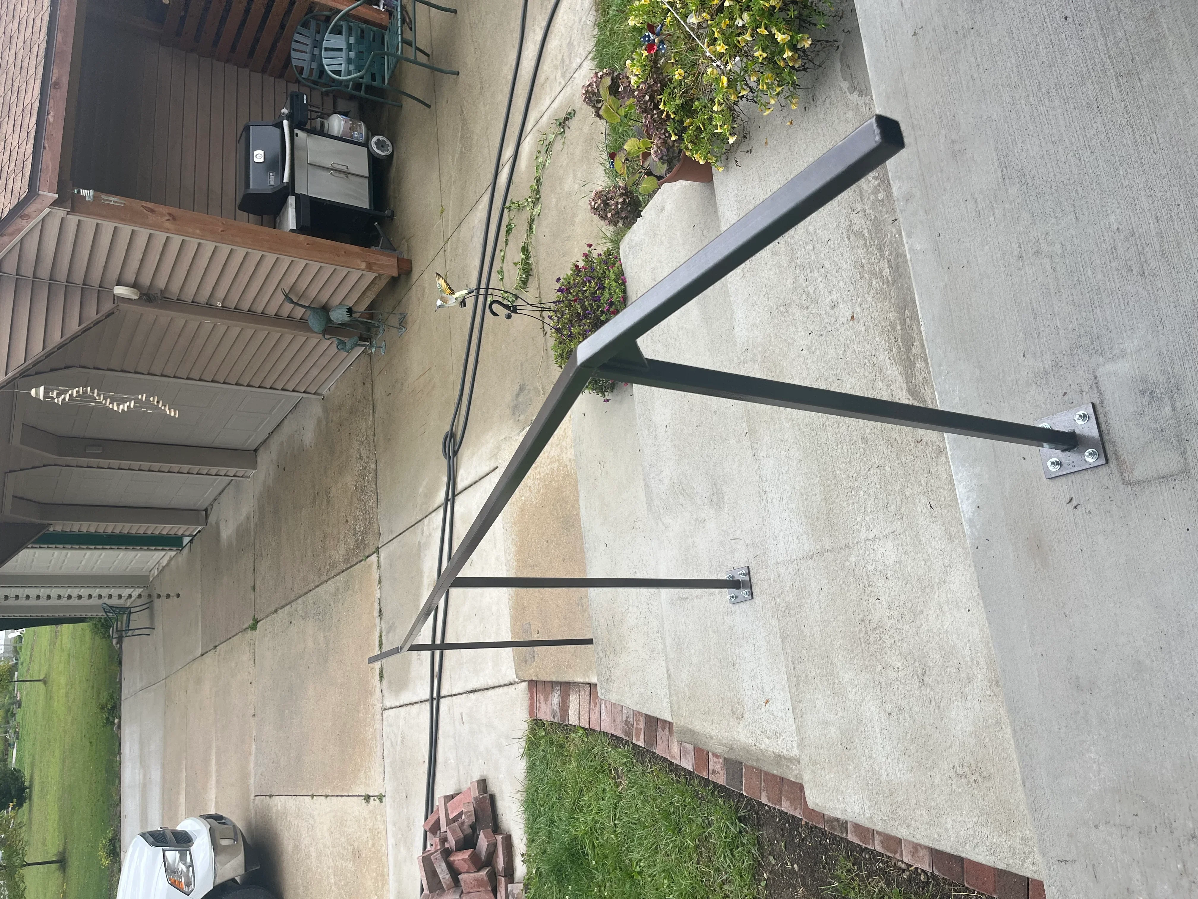 Black steel welded bracket with angled supports and mounting plates on concrete surface