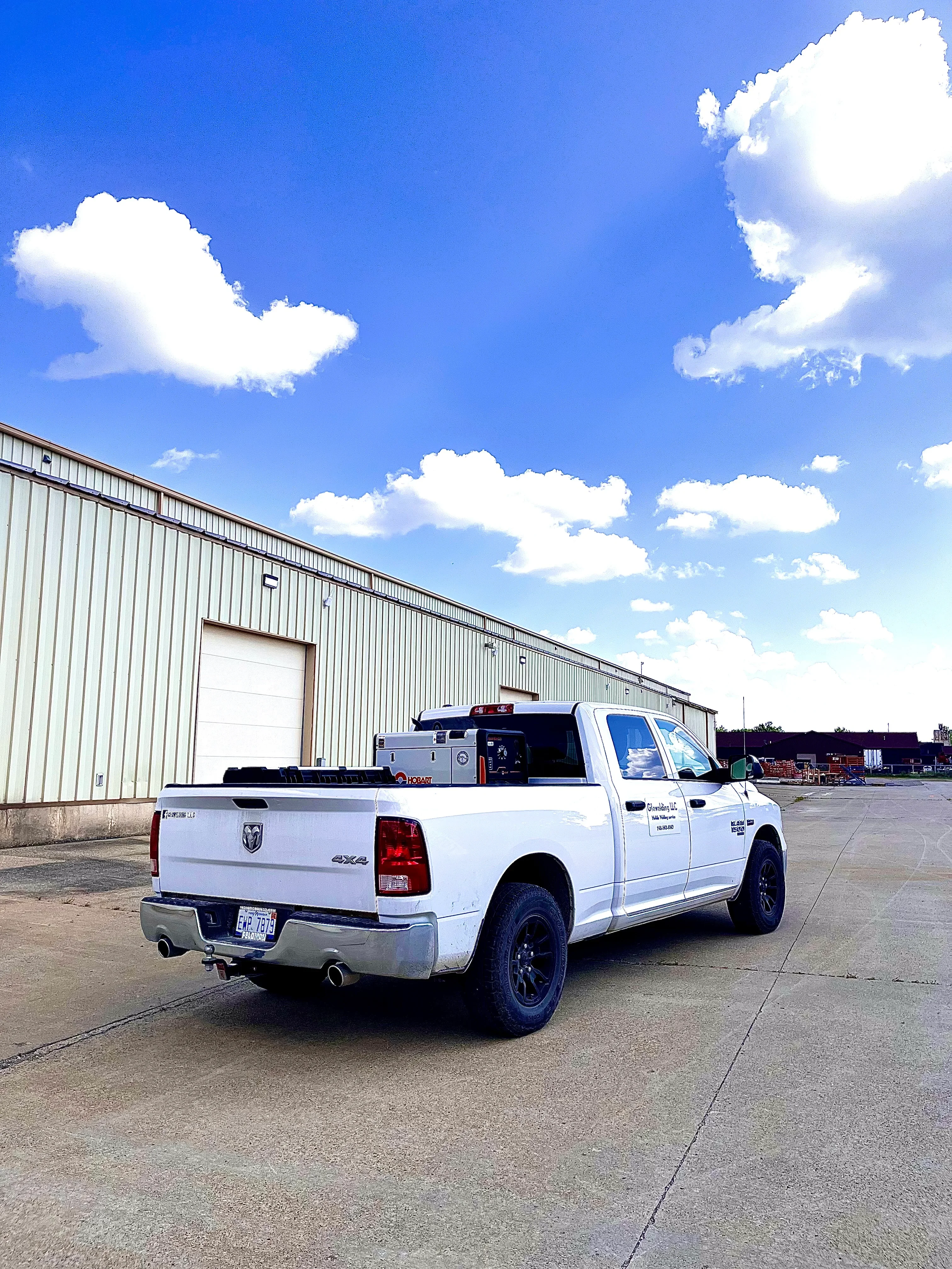 White pickup truck with custom welding equipment storage and toolboxes in bed